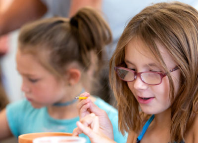 Two elementary-aged girls create a flower craft for their moms.
